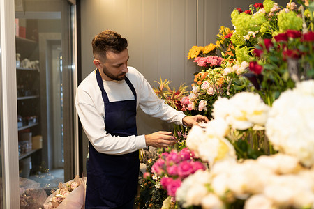 鲜花的男人摄影照片_在花店的冰箱里照顾鲜花的男人