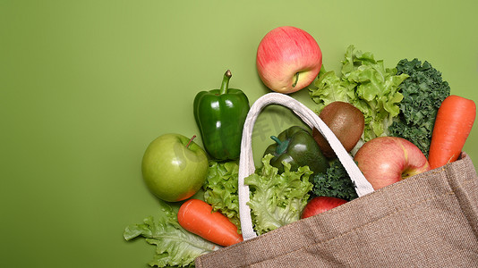 平铺中式底纹摄影照片_生态袋，配有绿色背景的各种生有机蔬菜和水果。