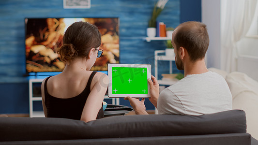 男子手持带绿屏的数字平板电脑与女友一起观看在线视频内容