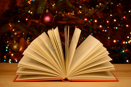 打开桌上的书，背景是装饰的圣诞树