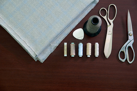 缝纫剪刀摄影照片_一组躺在木桌上的缝纫物，裁缝店的平铺概念