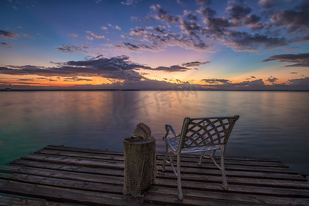 木码头上的空椅子在海边等待日出。