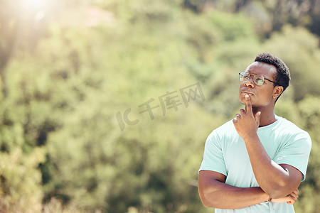 一位英俊的年轻非洲裔美国男性戴着眼镜在外面陷入沉思。自信的黑人在大自然中度过一天的同时做着白日梦。