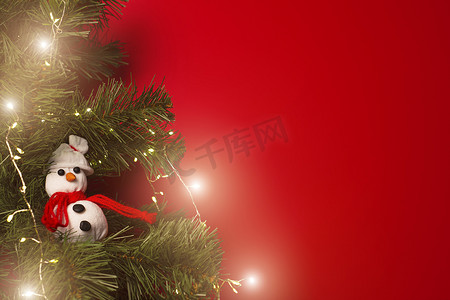 红色背景上装饰着花环和手工雪人玩具的圣诞树
