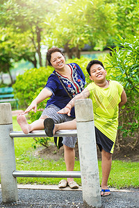 家庭锻炼摄影照片_肖像亚洲母子在花园里锻炼。在公园里运动的妇女和儿童伸展练习。户外放松和幸福的家庭时间概念。