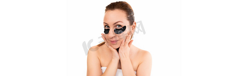 黑色斑块摄影照片_年轻女性接受水疗治疗后，眼袋上有黑色化妆品斑块