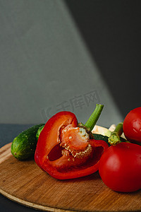 木板上鲜绿芦笋、辣椒、西红柿和黄瓜的枝条，深灰色背景，顶视图。