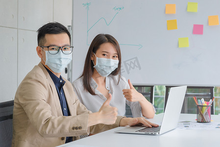 企业员工在办公室工作时戴口罩以保持卫生，遵守公司政策