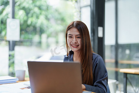 一位亚洲女员工第二天早上工作时面带微笑地使用电脑的肖像