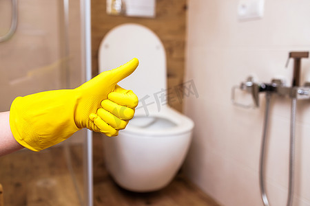 浴室背景上一只戴着黄色手套的手的特写