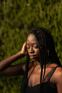 一位年轻黑人女性闭着眼睛摘下脸上的头发的肖像
