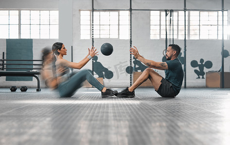 活跃、运动的健身情侣或健身伙伴一起训练，通过投掷加重的大满贯球来进行腹肌练习。