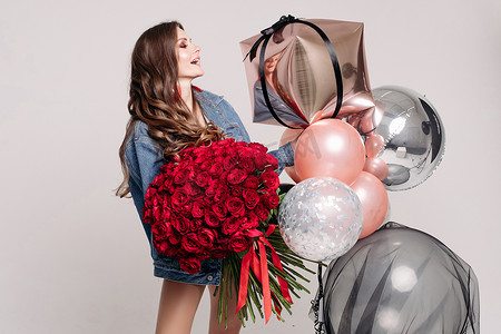 美丽的年轻女子与一束玫瑰和气球。