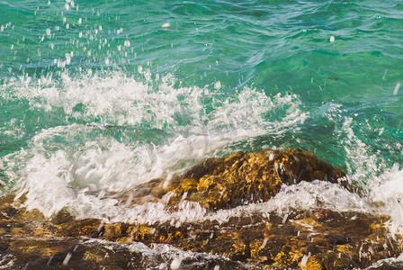 美丽清澈的绿松石海水表面照片，海景背景上有波纹和明亮的飞溅，水平图片