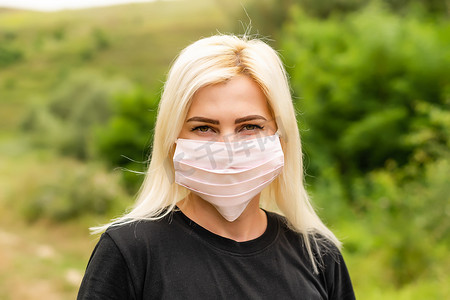 抵御病毒摄影照片_年轻漂亮女人的特写照片，她脸上戴着可重复使用的病毒防护面具，抵御冠状病毒。