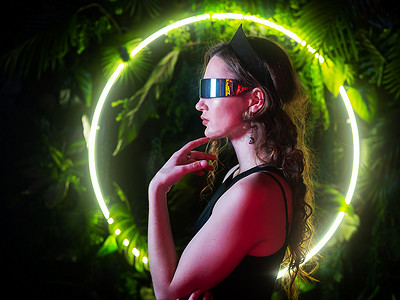 中环摄影照片_植物中环形霓虹灯背景下，戴着全景太阳镜的白人女性。