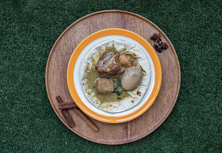 脆皮豆腐摄影照片_绿咖喱配炖猪腿、煮鸡蛋和自制皮塔面包上的豆腐。