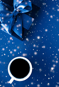 寒假礼盒、咖啡杯和蓝色平底背景上的发光雪，圣诞礼物惊喜