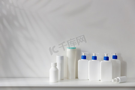 浴室的架子上放着带有蓝色分配器的白色瓶子，里面装有洗发水、护发素、奶油和液体肥皂。