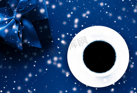寒假礼盒、咖啡杯和蓝色平底背景上的发光雪，圣诞礼物惊喜