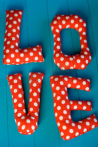 love摄影照片_蓝色木质背景上带有红色圆点织物“LOVE”的字母
