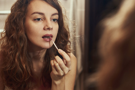 唇部护理摄影照片_在镜子前化妆的女人
