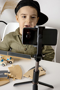 可爱、可爱的小男孩博主记录生活方式博客，与三脚架上的智能手机相机交谈。