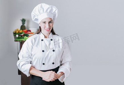 桌位摄影照片_一位被新鲜蔬菜包围的女厨师的肖像，一位穿着制服的女性营养师的肖像，桌上摆着新鲜蔬菜，一位女性营养师，一桌蔬菜
