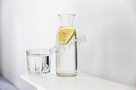 一杯清爽的水，一瓶里面有一片柠檬的瓶子，在炎炎夏日的梳妆台上