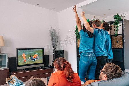 朋友们在球队获胜后欢呼雀跃，观看电视上的足球比赛。