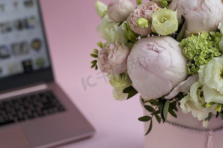 盒子粉色摄影照片_在打开的笔记本电脑的背景下，一束鲜花放在盒子里