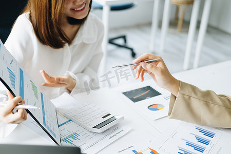 谈判、分析、讨论、亚洲女经济学家和营销人员指着财务数据表来规划投资，以防止公司的风险和损失
