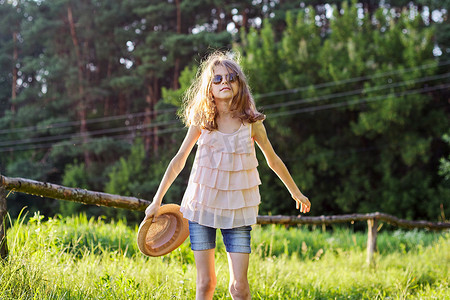 享受暑假的快乐女孩，大自然中的孩子在绿色草地上玩帽子