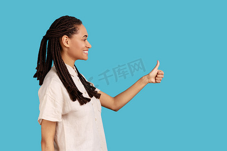 手机侧视图插画摄影照片_留着辫子的女人的侧视画像开心地笑着，竖起大拇指，赞同某事。
