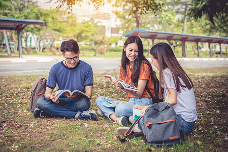 一群亚洲大学生在户外草地上读书并辅导特别班考试。