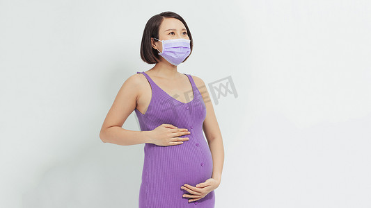 年轻孕妇母亲戴着冠状病毒疾病防护面罩，脸上挂着快乐而冷静的微笑。