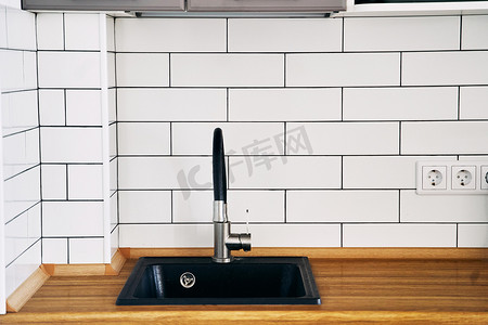 厨房的木制台面上时尚的黑色水槽和水龙头特写