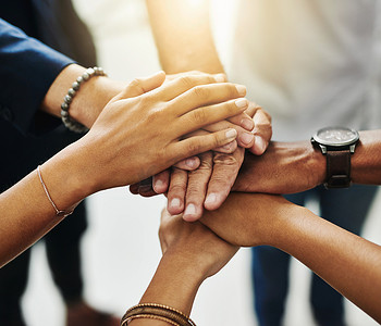商界人士双手叠在一起，在多元文化或多元化的业务团队中表现出团结、团队合作和协作。