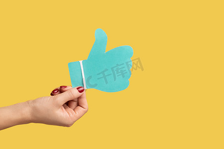 女性手的特写显示社交媒体蓝色大拇指图标，推荐支持。