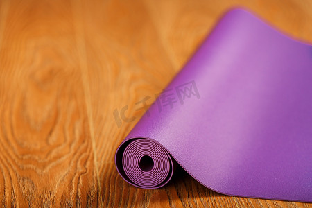 一张展开的淡紫色瑜伽垫铺在木地板上。