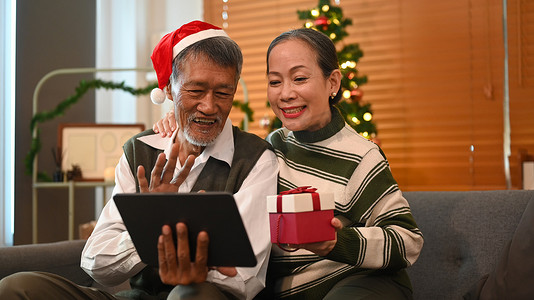 在圣诞节假期里，一对恩爱的年长夫妇在数字平板电脑上与朋友或家人进行视频通话