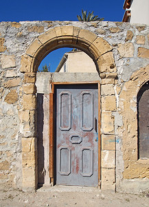 尼科西亚塞浦路斯阳光明媚的街道上，古石墙上拱形框架中的旧木门