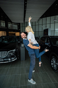 幸福的白人夫妇在汽车经销店购买新车时拥抱。