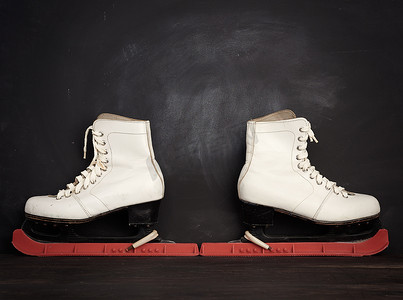 花样鞋带摄影照片_用于花样滑冰的白色皮革溜冰鞋站在棕色木质上