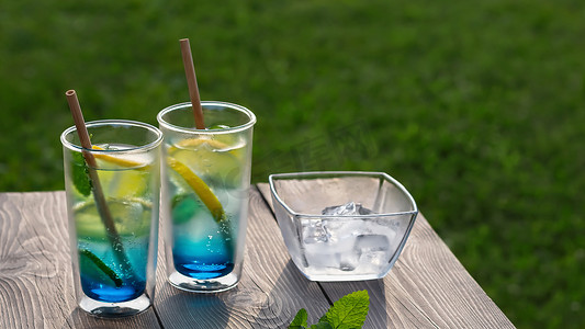 蓝色清爽夏季摄影照片_木桌上有两杯夏季凉爽的蓝色泻湖鸡尾酒。