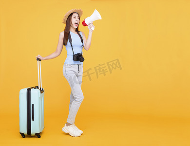 快乐的年轻女人带着行李和拿着扩音器隔离在黄色背景、夏天、旅游概念。