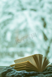 冬天的书摄影照片_窗外的雪和打开的书