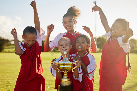 奖杯胜利摄影照片_儿童、足球奖杯和足球场体育比赛获胜队，用于在户外比赛后庆祝进球、胜利和团队合作。