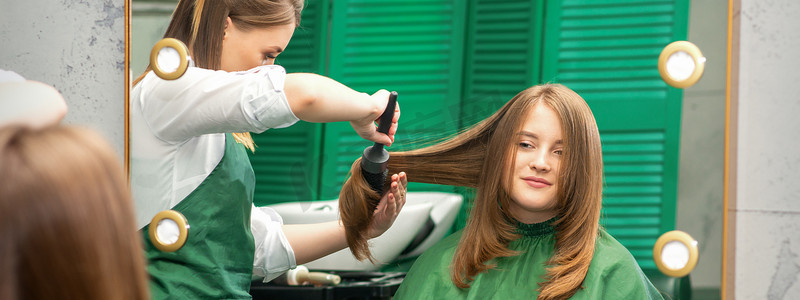 美发师一边用梳子梳头一边为女人做发型，在美发沙龙梳头。