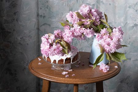 复活节蛋糕、彩绘鸡蛋和桌上的一束粉色樱花